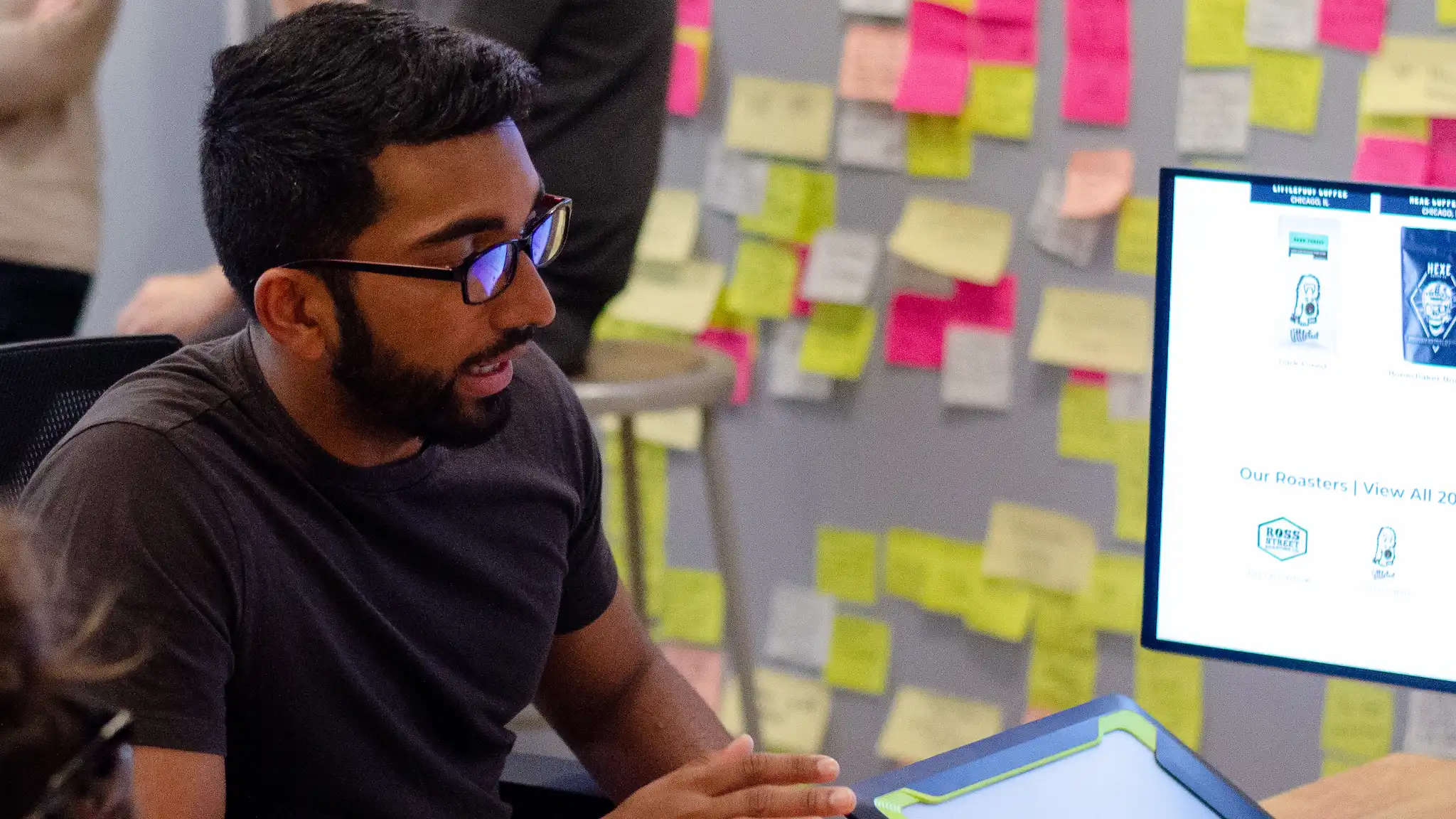 Bejoy reviewing design work in front of a wall of sticky notes.