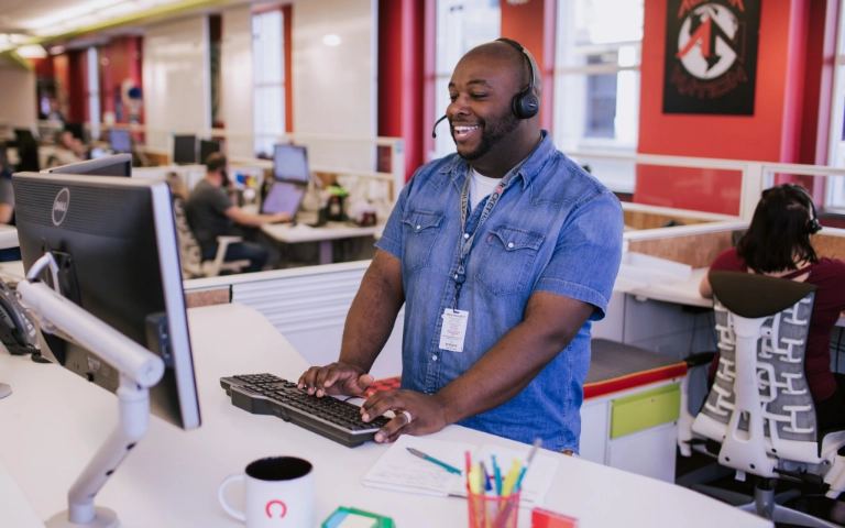 A stock photo of a crowded Rocket Companies office, with a team member working at a workstation.